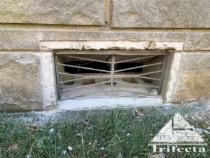 Bedford stone home foundation vent during vent guard installation process