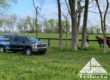 Trifecta Wildlife Services truck parked along some horses on a Lexington KY farm.