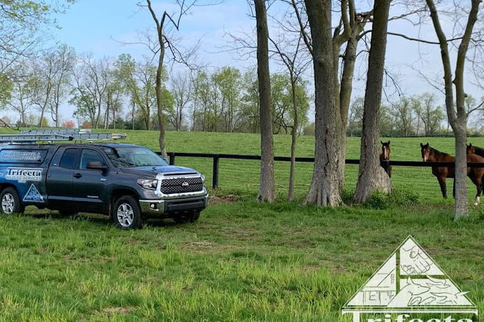 Trifecta Wildlife Services truck parked along some horses on a Lexington KY farm.